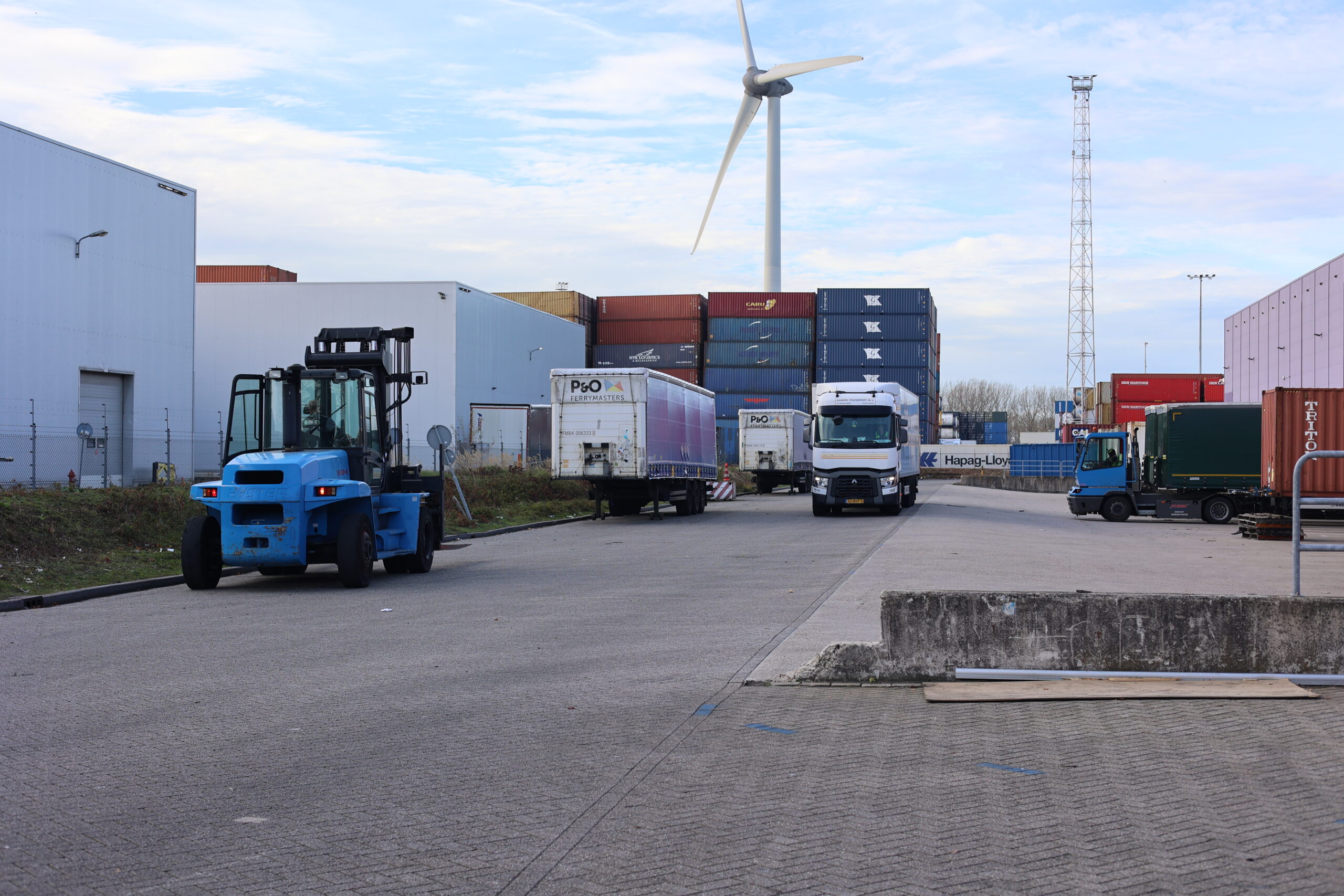 Picture of multiple trucks and big blue forklift on parking lot