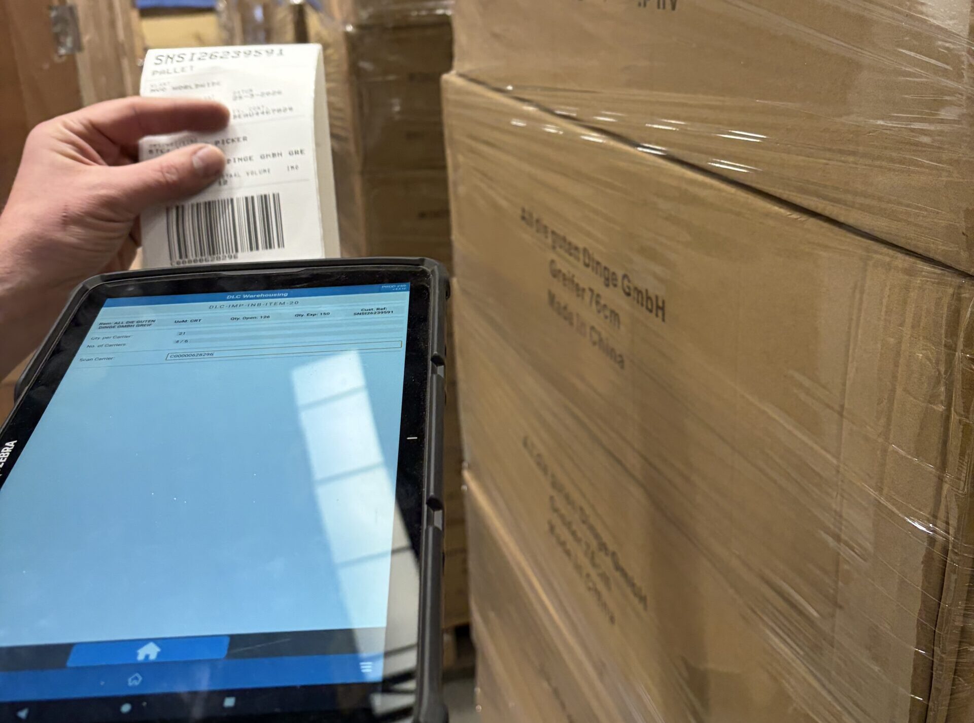 Person holding a label and a tablet next to cardboard boxes