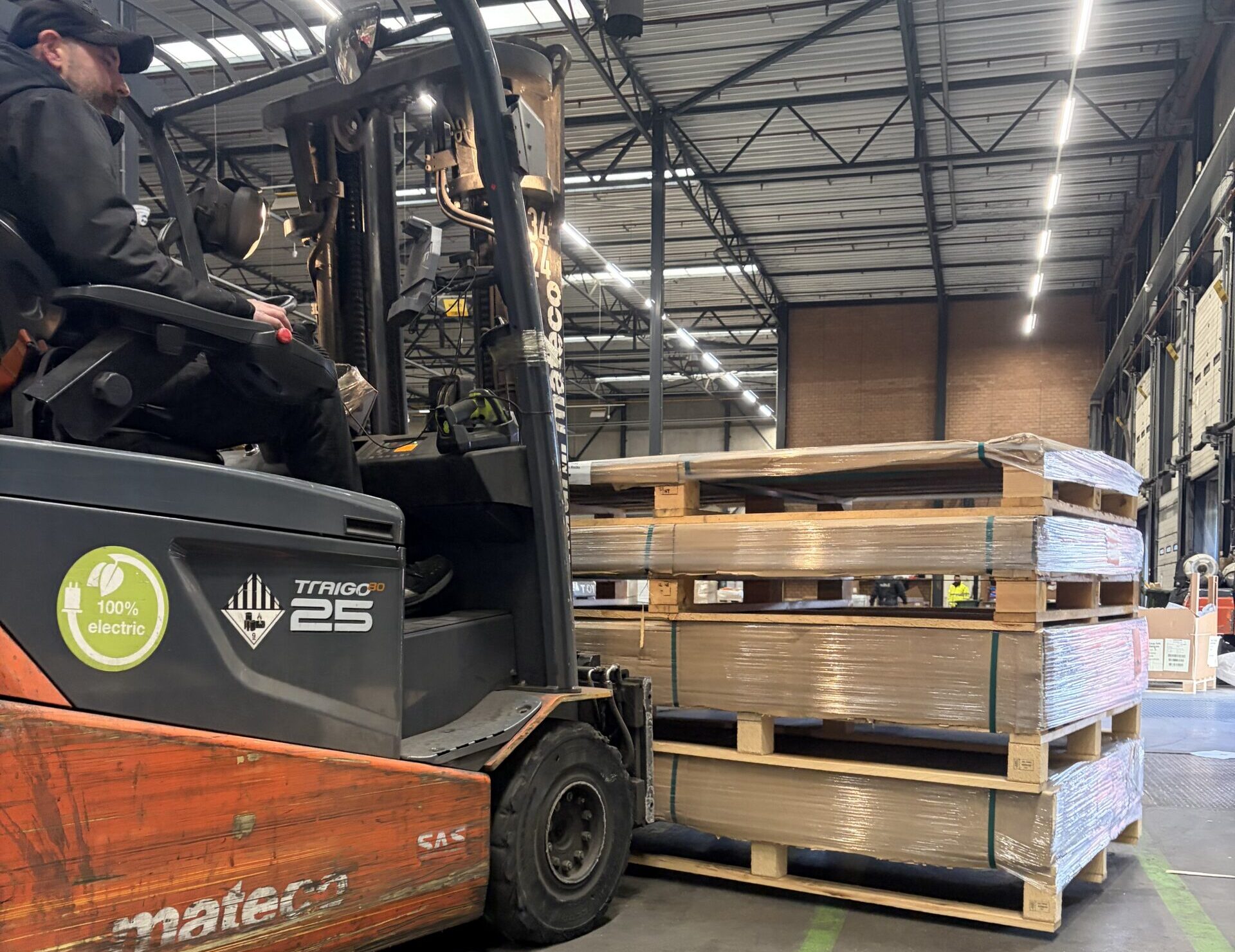 Orange forklift moving a crate inside a warehouse
